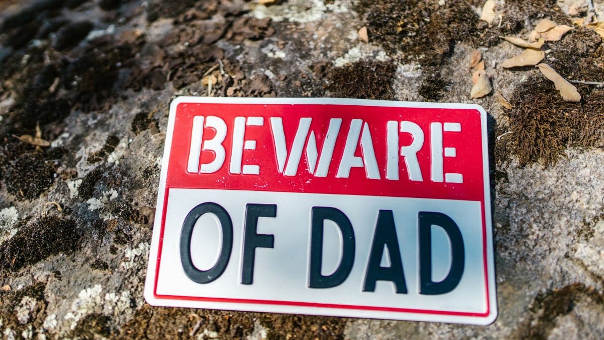 A playful 'Beware of Dad' sign placed outdoors, offering a humorous warning.