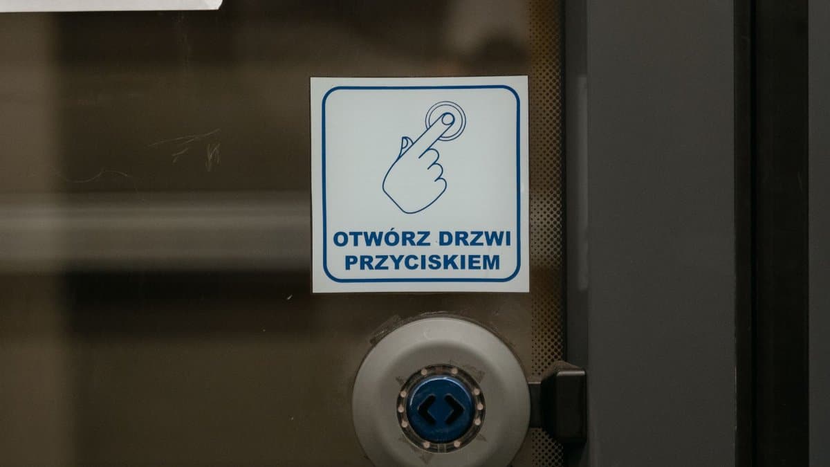 Close-up of a door with Polish push button sign in a public place.