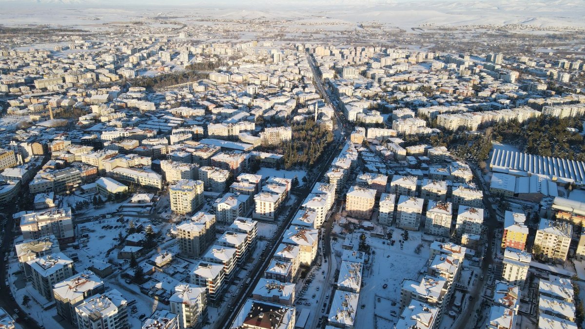 Aerial view of a city covered in snow during winter, highlighting urban architecture and streets.