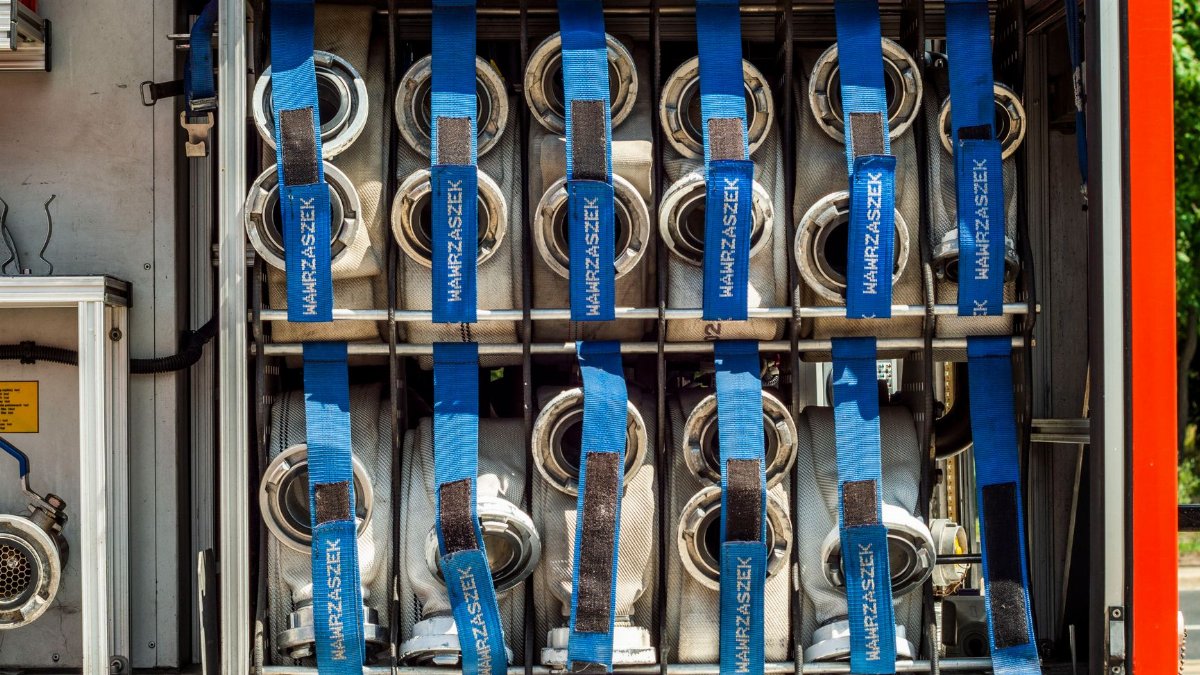 Close-up of fire truck hose storage with blue straps and equipment neatly organized.
