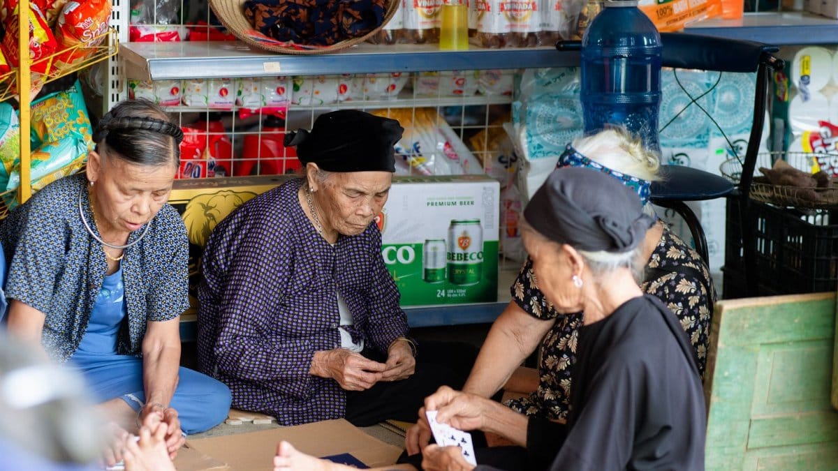 A group of elderly women playing cards in a traditional Vietnamese market setting, Ha Giang, Vietnam.