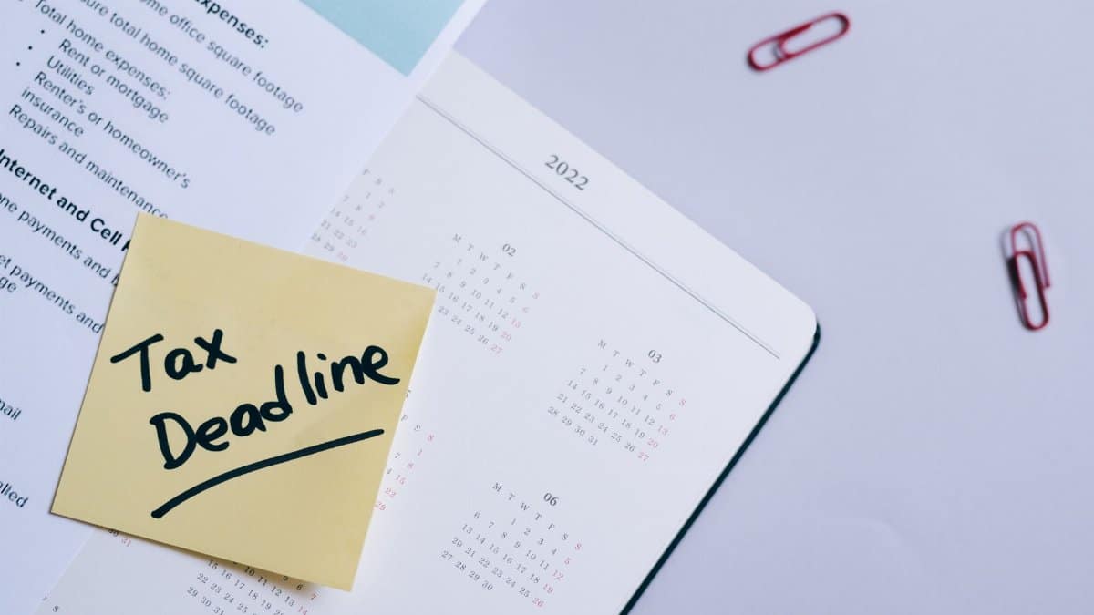A sticky note highlights tax deadline on a calendar alongside documents, emphasizing financial planning.