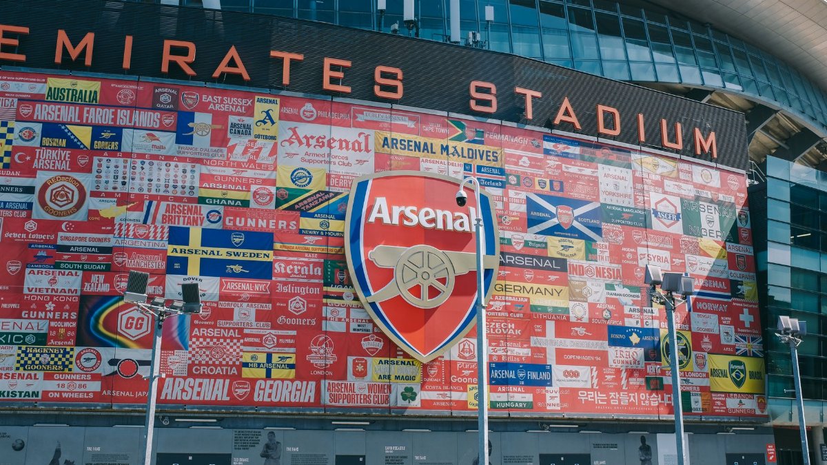 Vibrant wall art at Emirates Stadium featuring Arsenal flags and crest in London, UK.