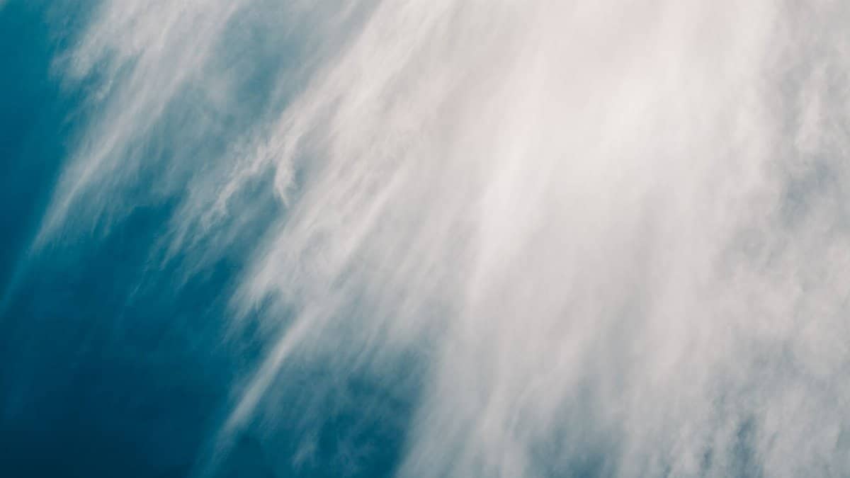 A striking abstract cloudscape featuring wispy white clouds against a deep blue sky, evoking a sense of tranquility.