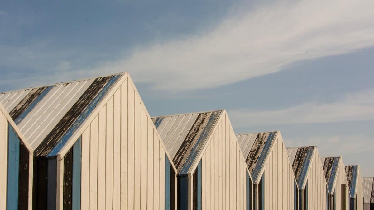 Row of coastal beach huts in Yport, Normandy against a clear sky.