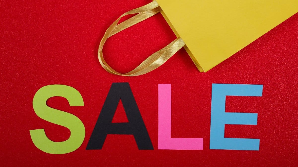 Eyecatching sale signage with a yellow shopping bag on a vibrant red background.