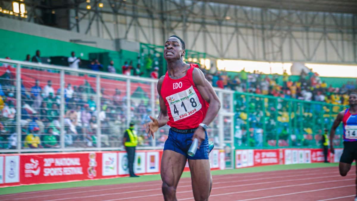 A focused athlete in a relay race at a national sports festival, showcasing determination and speed.