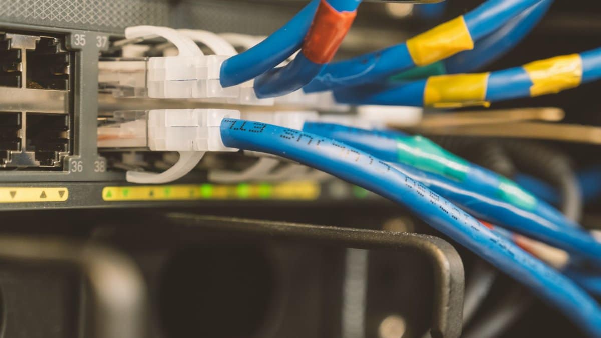 Network switch and blue ethernet cable with white tips connected to system for maintenance