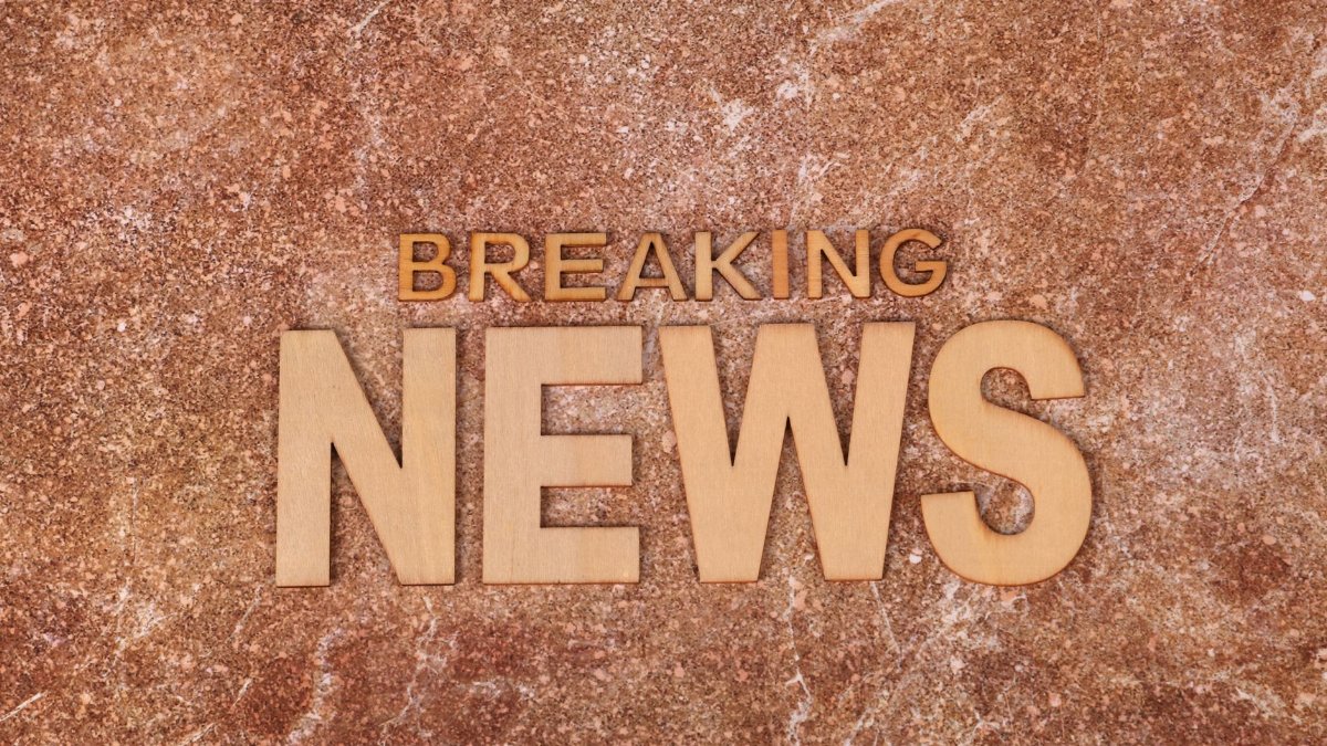Wooden letters spell 'Breaking News' on a textured, marble-like background. Ideal for newsworthy content.
