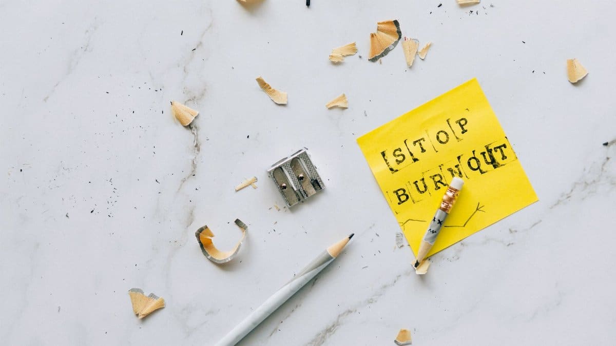 Overhead shot of a note saying 'Stop Burnout' on a marble surface with pencil shavings.