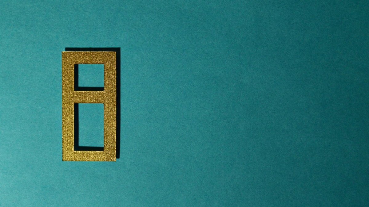 Golden number eight cutout on a teal background, perfect for decorative purposes.