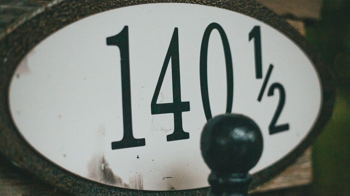 Close-up view of an old house number plate reading 140½ with a black decorative element.