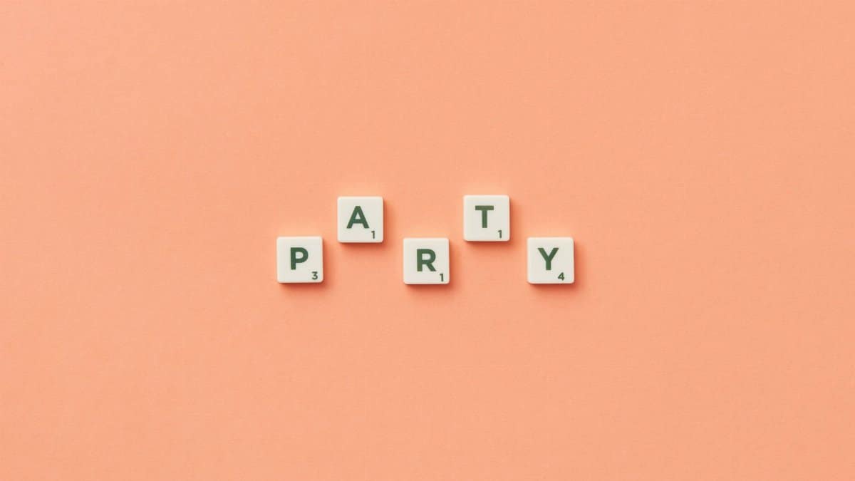 Scrabble tiles forming the word party on a minimalist peach backdrop, perfect for celebrations.