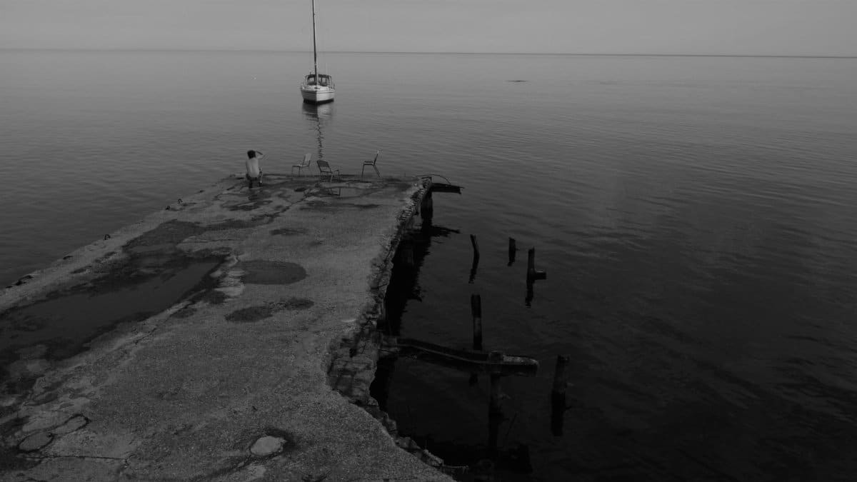 A peaceful scene of a pier with a solitary boat on a still water surface at twilight.