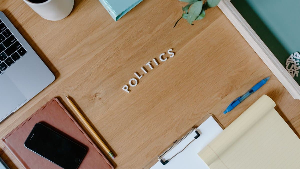 Overhead shot of a workspace with a politics theme, featuring a laptop, planner, and clipboard.