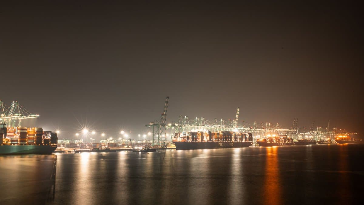 Luminous night view of a bustling industrial port with cargo ships.