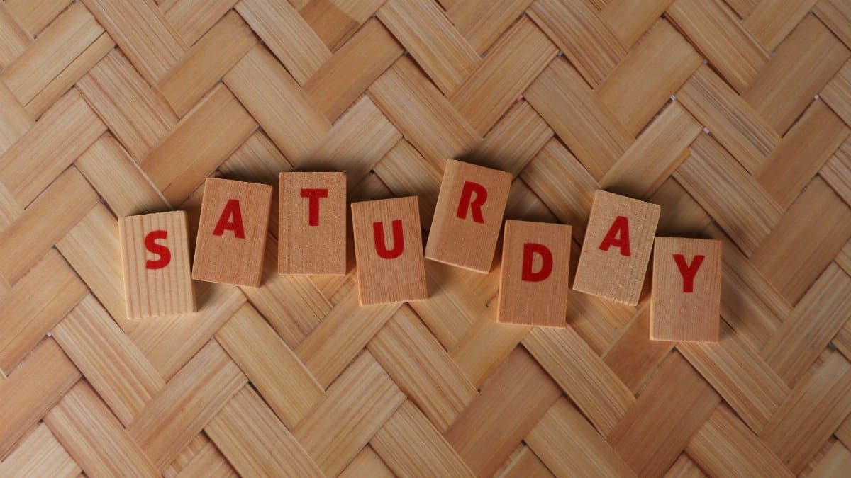 Wooden blocks on a woven surface spelling the word Saturday in red letters.