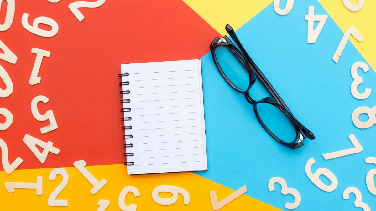 Vibrant flat lay featuring notebook, eyeglasses, and wooden numbers on colorful background.