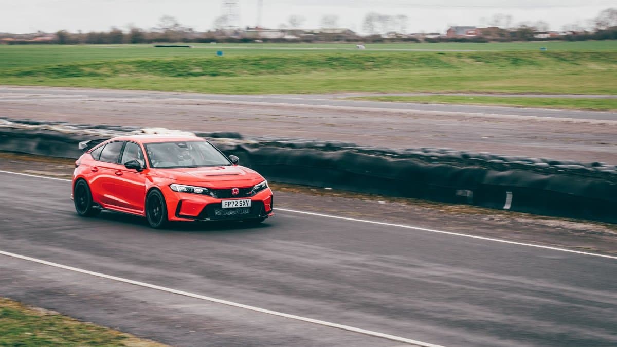 Dynamic shot of a red Honda Civic Type R speeding on a racetrack in Blyton, England.