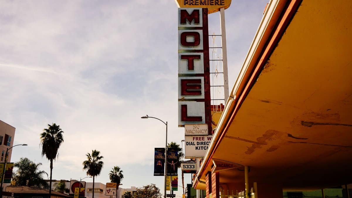 Iconic Hollywood Premiere motel sign against a California sky, framed by palm trees.