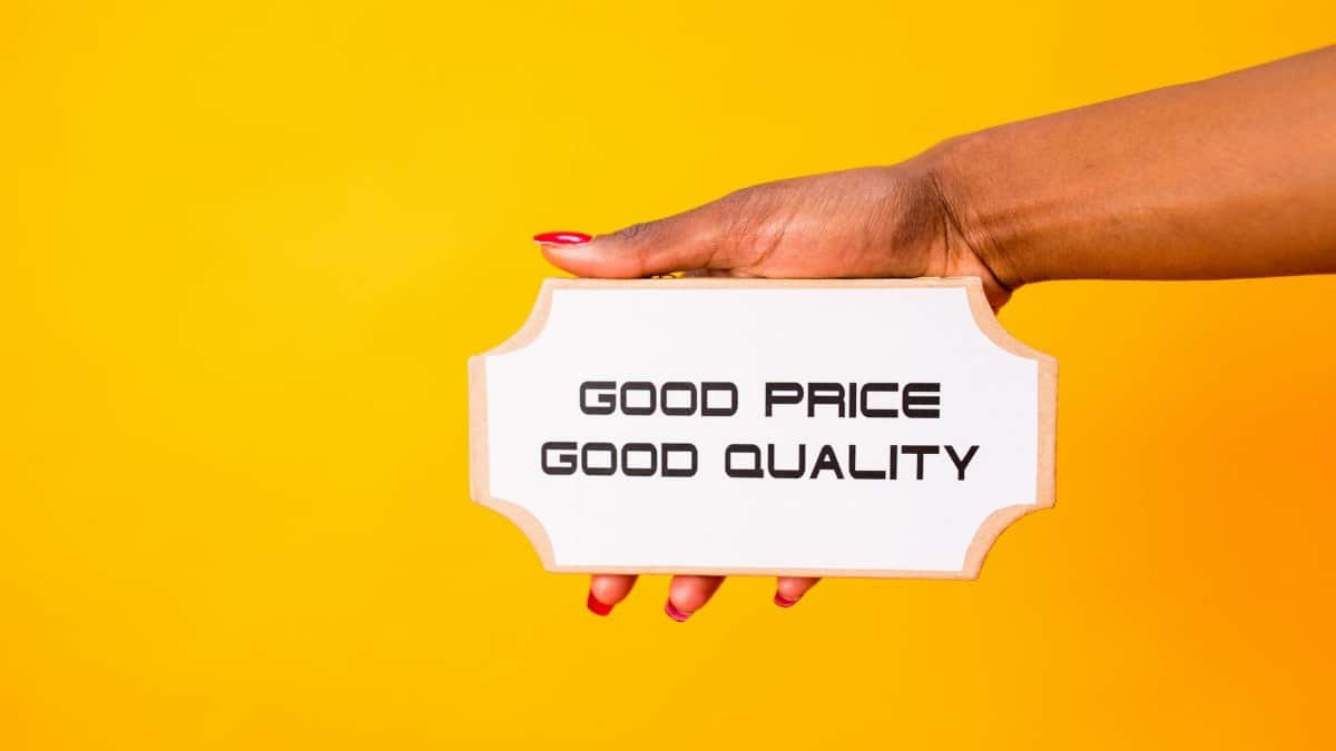 A hand holding a sign with 'Good Price Good Quality' against a vibrant yellow background.