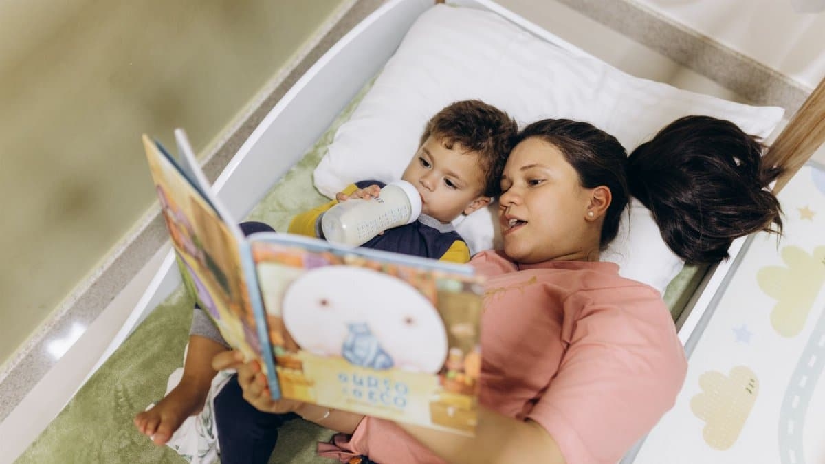 A mother reads to her young son in bed, creating a bonding bedtime routine.