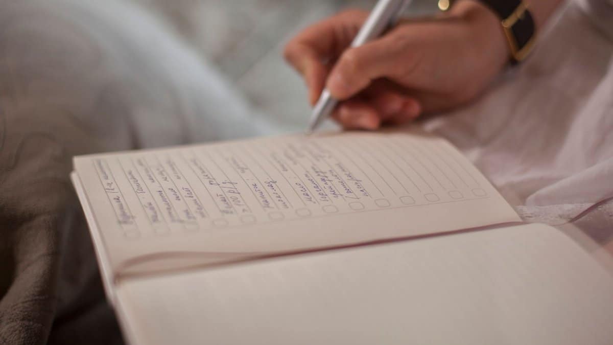 A close-up image of a person's hand writing in a notebook, emphasizing focus and creativity.