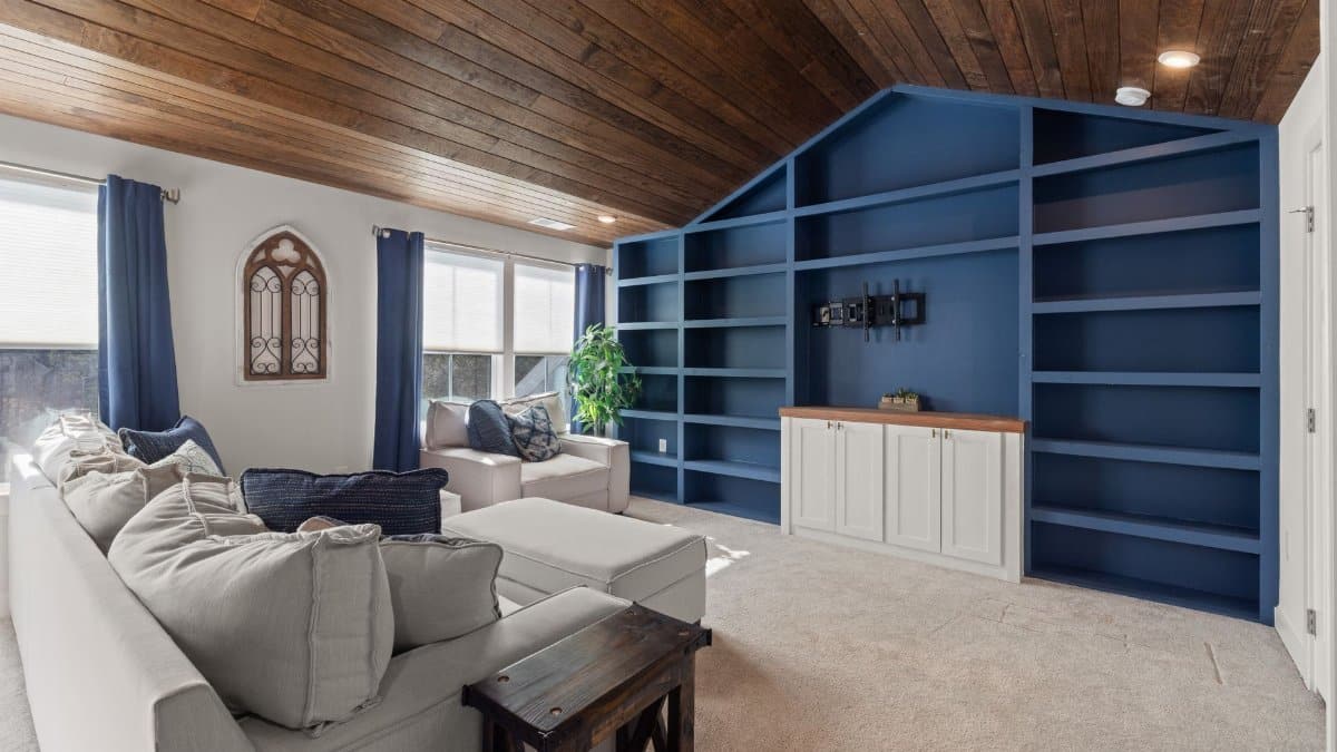 Spacious living room featuring blue built-in shelves and a plush beige sofa with natural light.