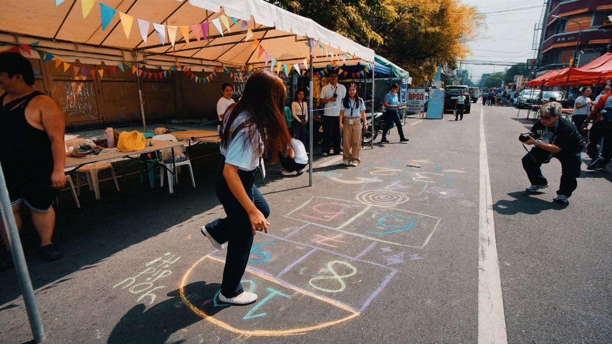 Outdoor street festival featuring a colorful hopscotch game with people enjoying the event.