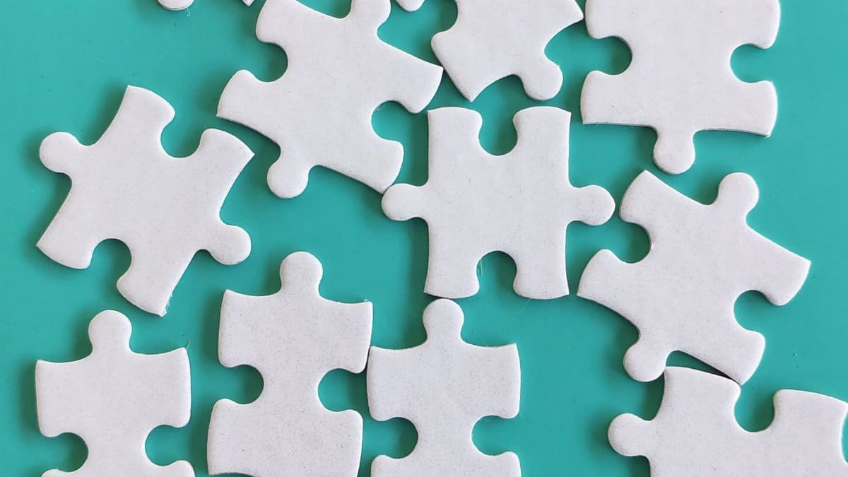 Random white puzzle pieces arranged on a teal background, creating a simple yet intriguing pattern.