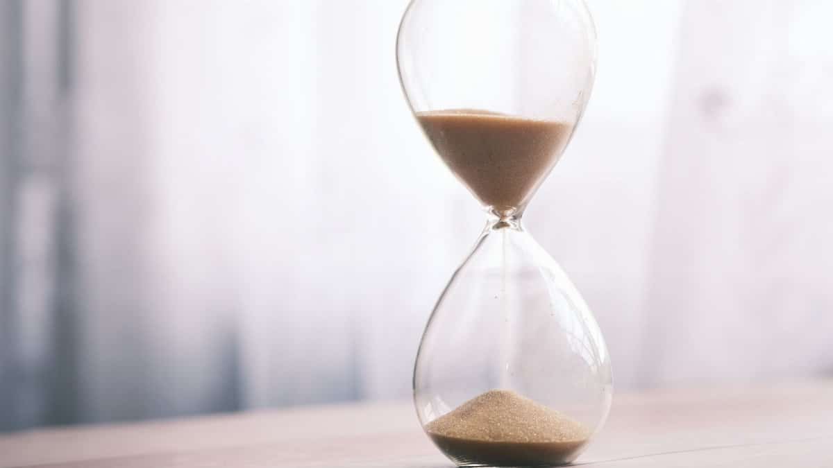 Minimalist hourglass filled with sand symbolizing time and patience, against a soft background.