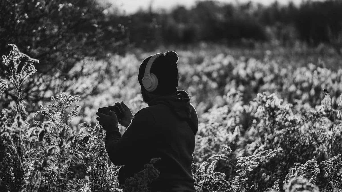 Adult in headphones enjoys autumn in Kitchener, Ontario field.