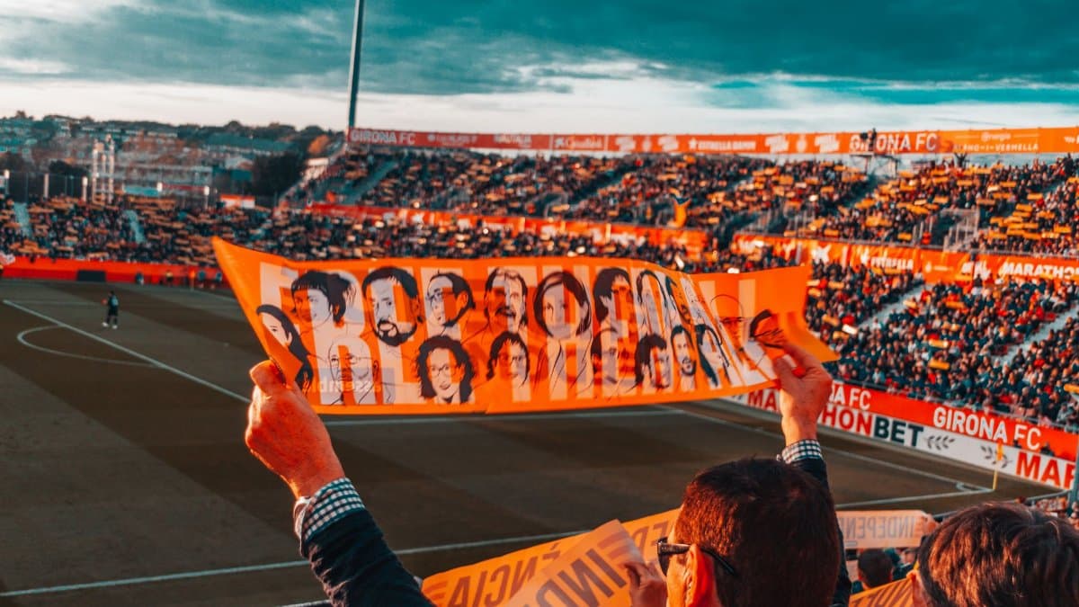 Energetic crowd at Girona FC stadium holding a vibrant banner during a football match.