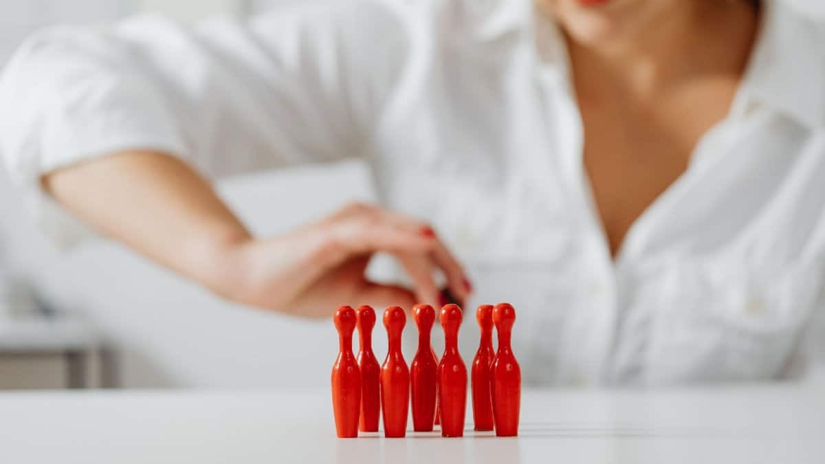 A focused woman arranging small red skittles on a white table indoors.