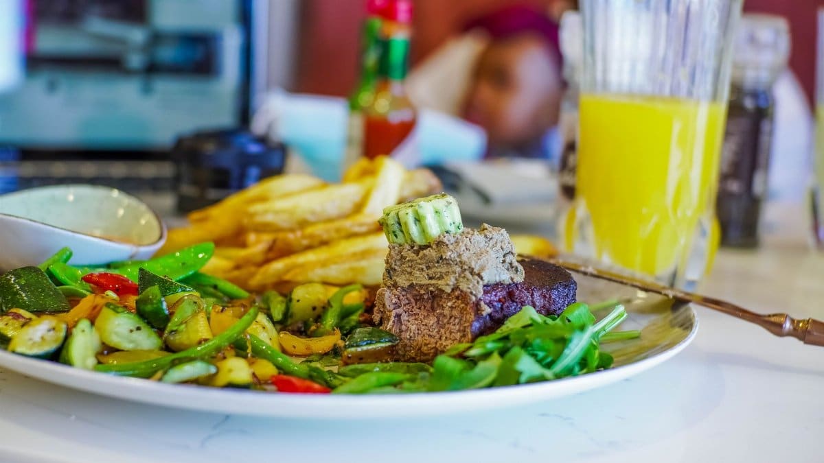 Vibrant South African dish featuring steak, vegetables, and fries served with a refreshing drink.