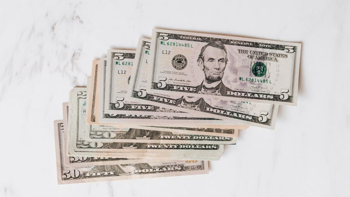 Top view heap of american dollar bills in different denominations placed on marble surface