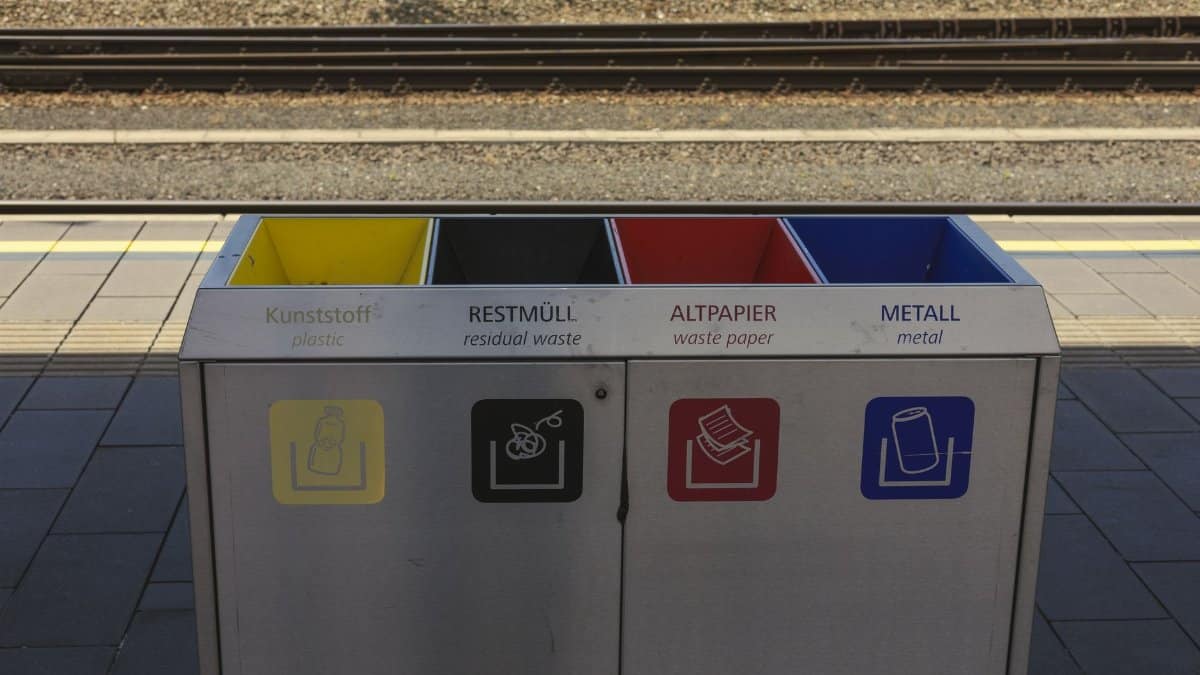Color-coded recycling bins at a train station, promoting waste separation and environmental sustainability.