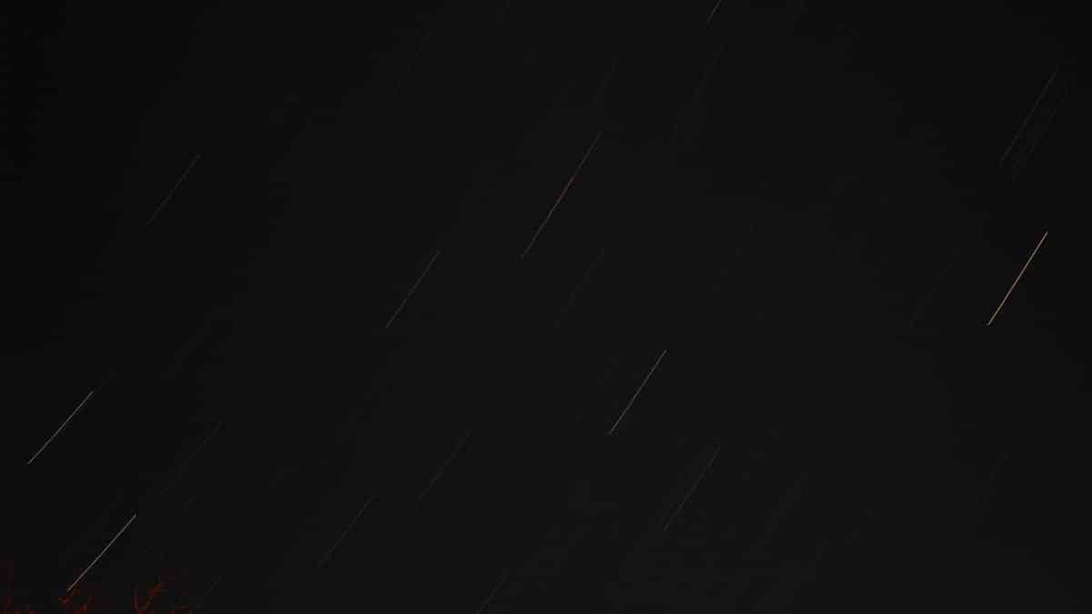 Long exposure shot of star trails and light streaks in the night sky.