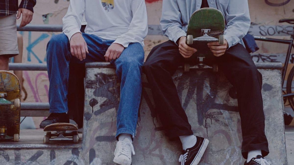 Young skaters sitting on a ramp at an urban skatepark, showcasing street style and skateboarding culture.