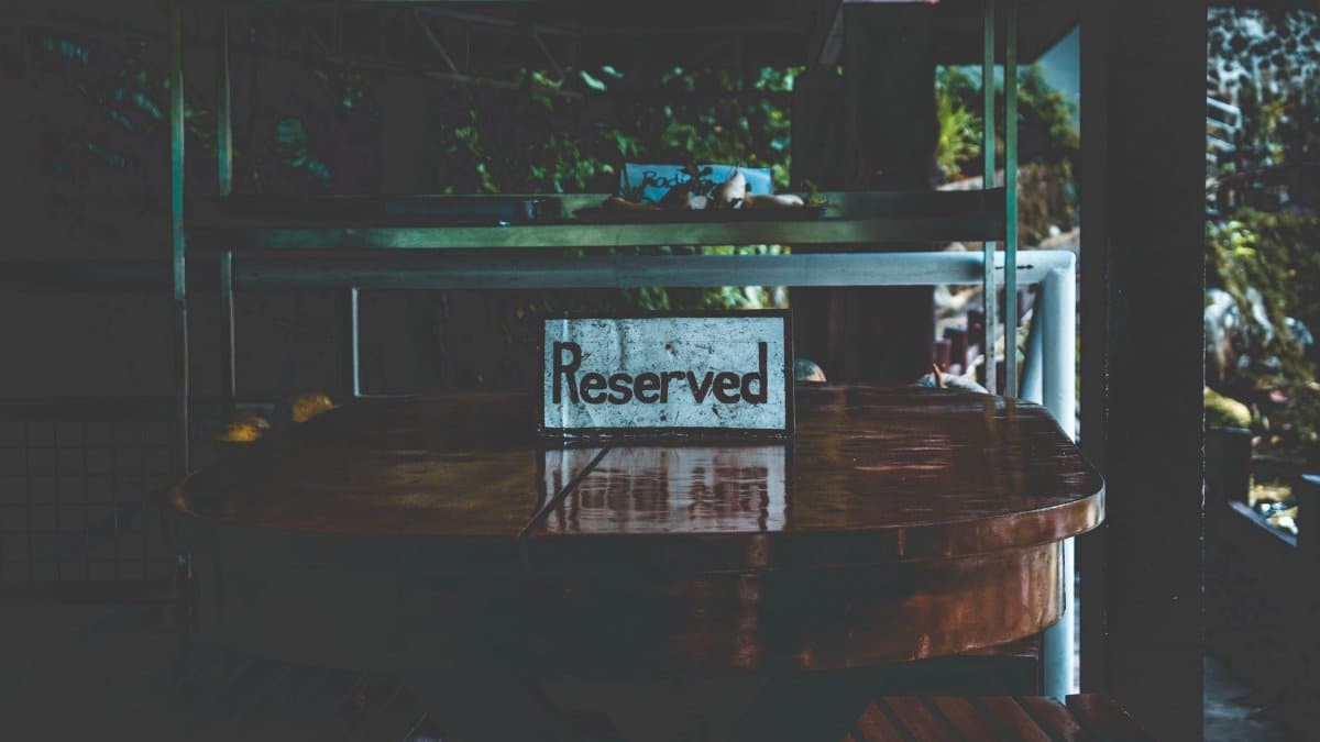 A dimly lit table with a reserved sign, set in an outdoor environment creating a moody atmosphere.
