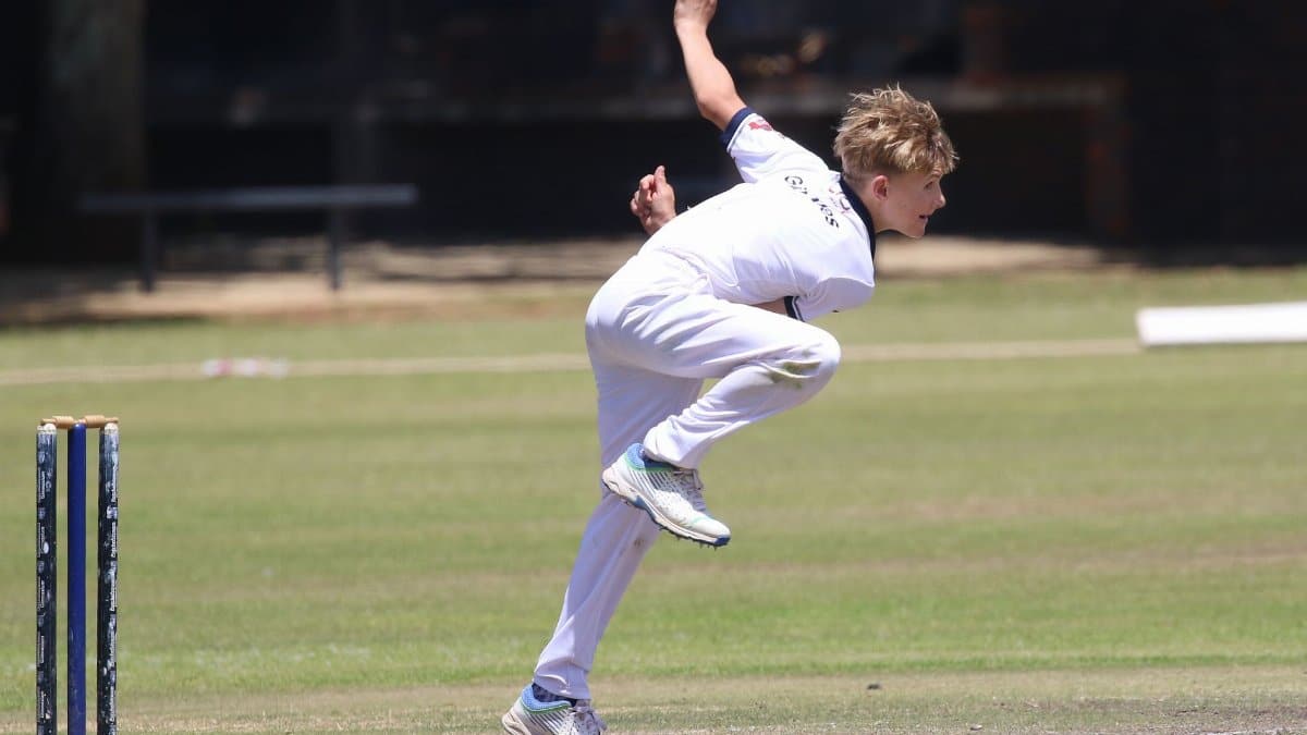 Young cricketer in action on a sunny day, captured mid-bowling with intense focus.