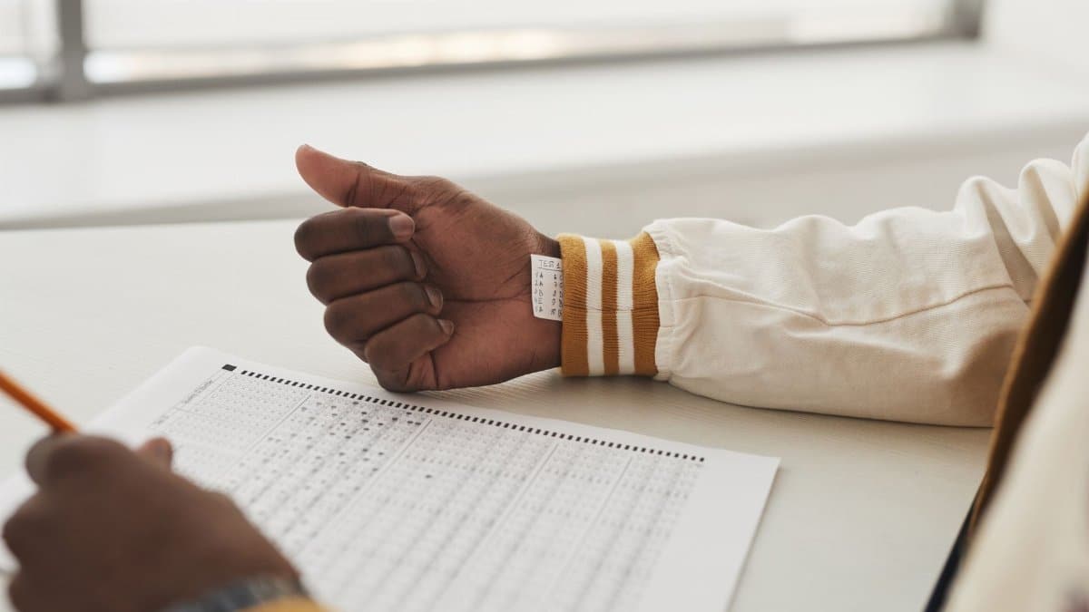 Close-up of a student cheating in an exam by hiding notes under a sleeve during a test.