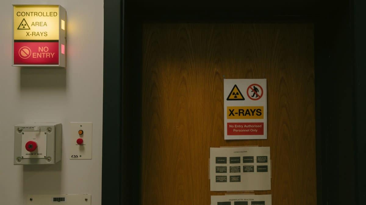 Warning signs on a wooden door indicating a controlled X-ray area with no entry restriction.