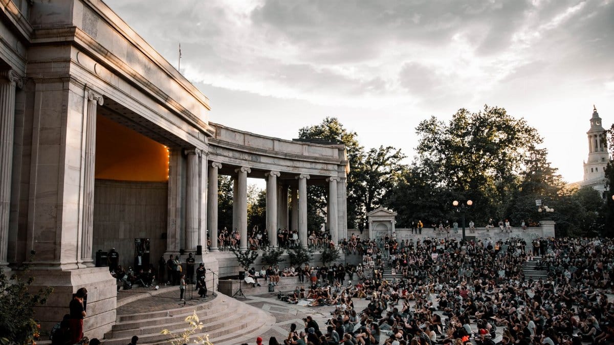 A large crowd gathers at the Greek Theatre in Denver during sunset for a public event.