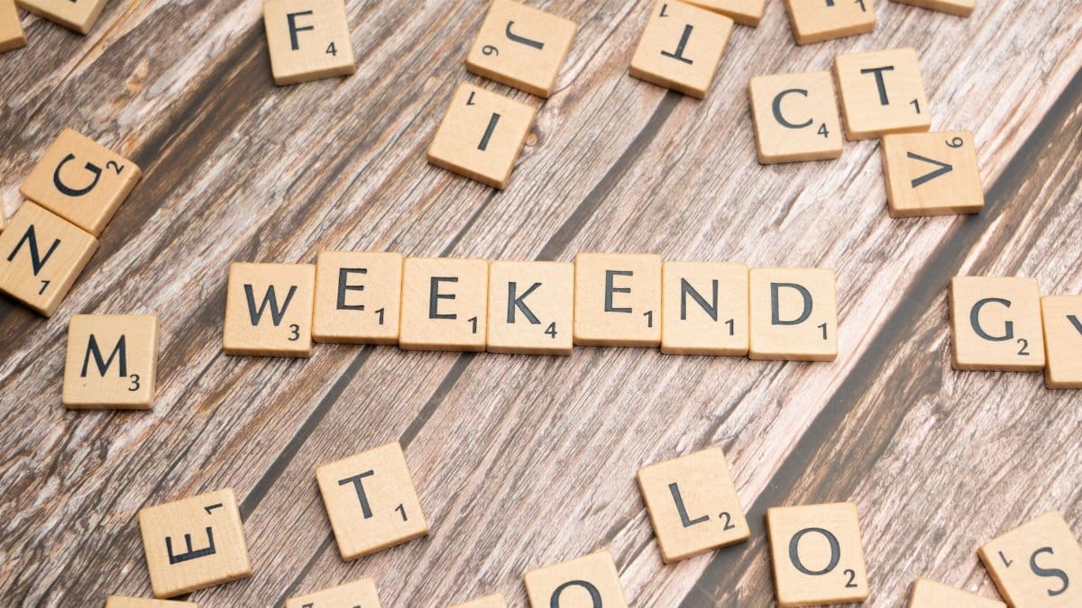 Wooden Scrabble tiles spelling 'weekend' on a rustic wooden table.