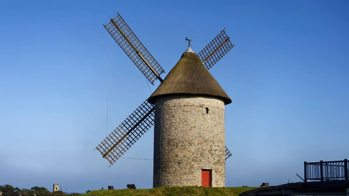 A traditional windmill tower in Skerries, Ireland, under a clear blue sky.