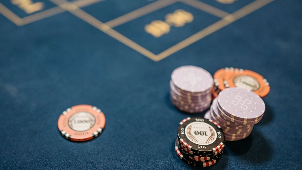 A detailed view of poker chips on a blue gaming table, perfect for gambling themes.
