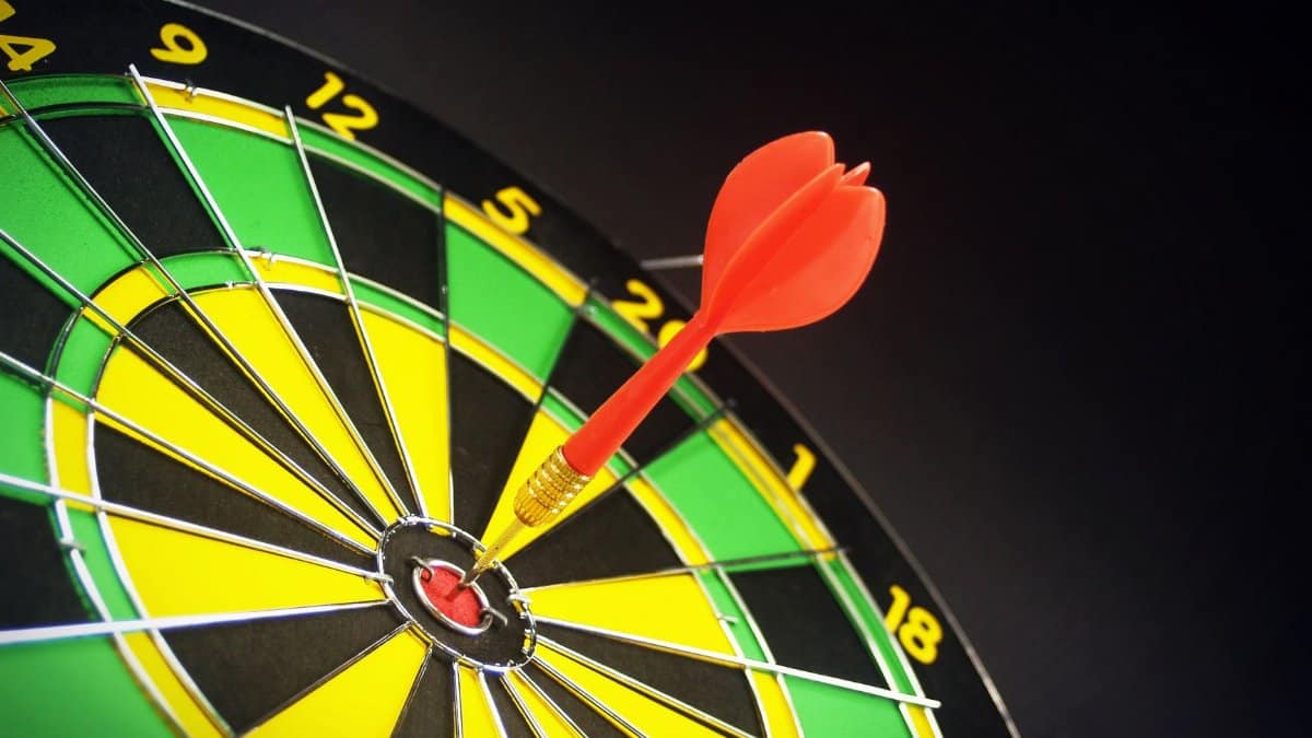 Close-up of a dart successfully hitting the bullseye on a bright dartboard, signifying victory.