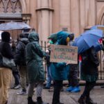 Activists protest for abortion rights in a rainy New York street. Umbrellas and placards visible.