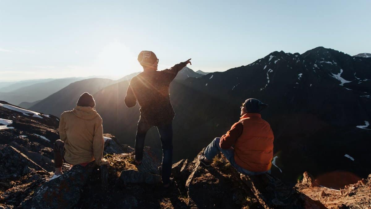 Three adults enjoy a scenic mountain view at sunrise, capturing the essence of outdoor adventure.